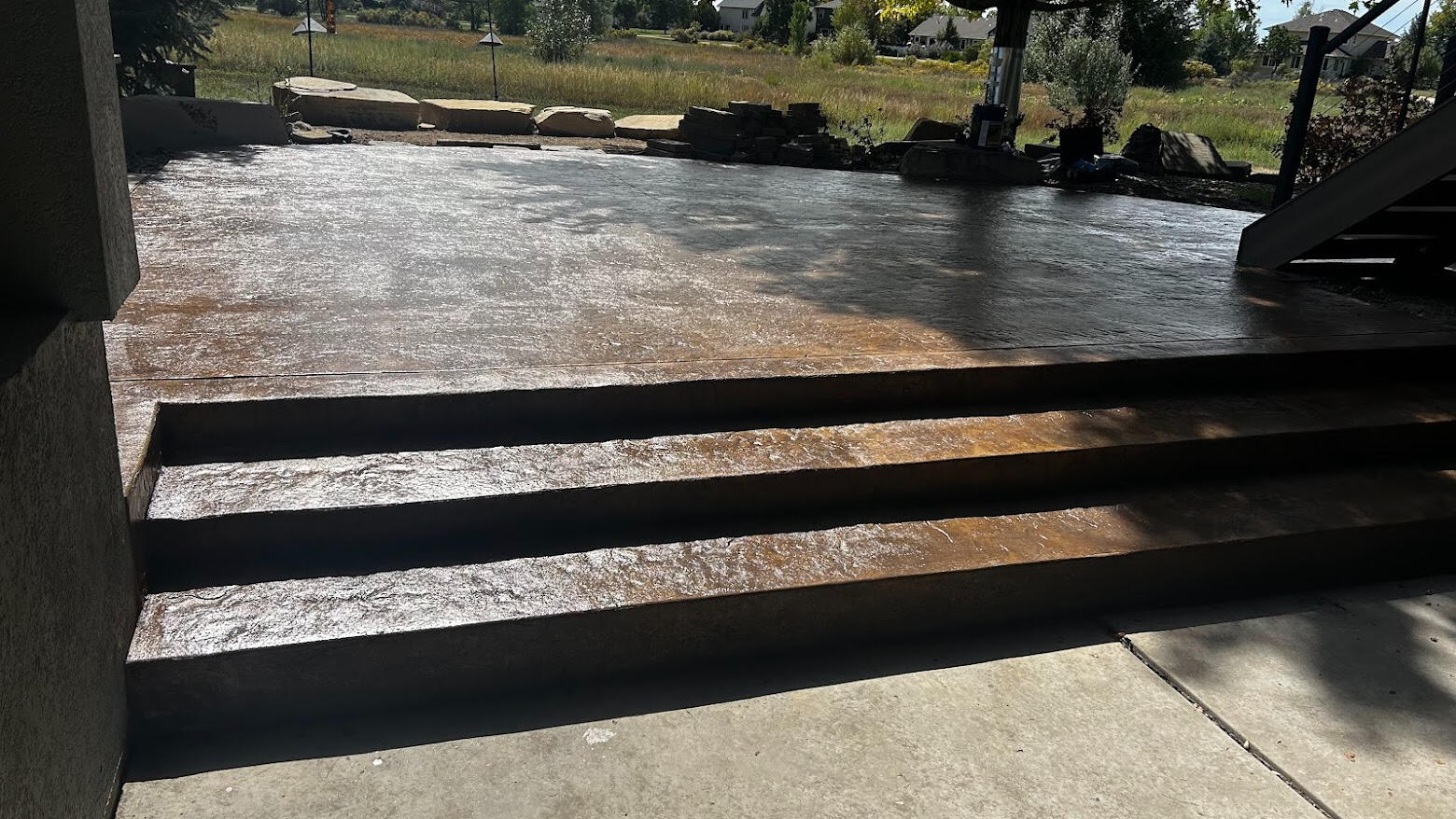 Stamped Concrete Stamped concrete patio with steps in Fort Collins, Colorado featuring a dark decorative finish for a modern outdoor living space