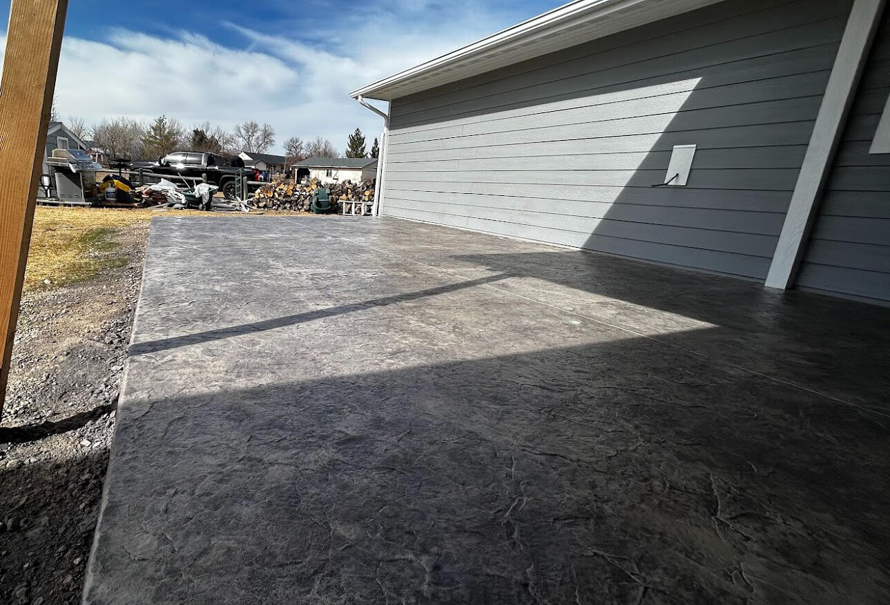 Stamped concrete backyard patio in Loveland, CO with a gray textured finish, ideal for low-maintenance outdoor entertainment