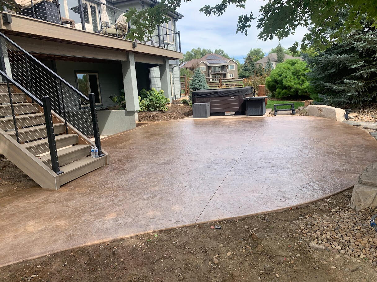 Stamped concrete backyard patio in Fort Collins, Colorado with a rock textured finish, perfect for outdoor entertainment.