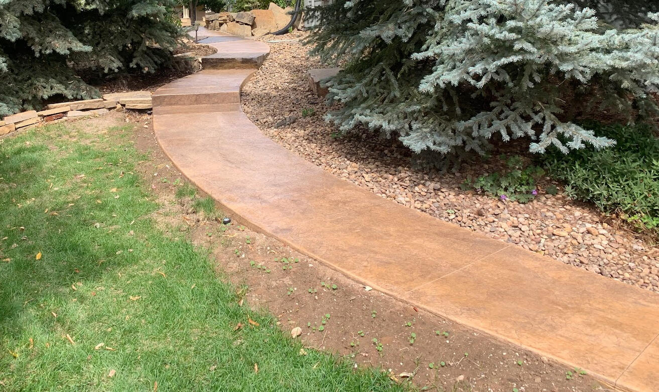 Curved stamped concrete walkway in Fort Collins, CO with a natural stone texture, designed for durability and longevity