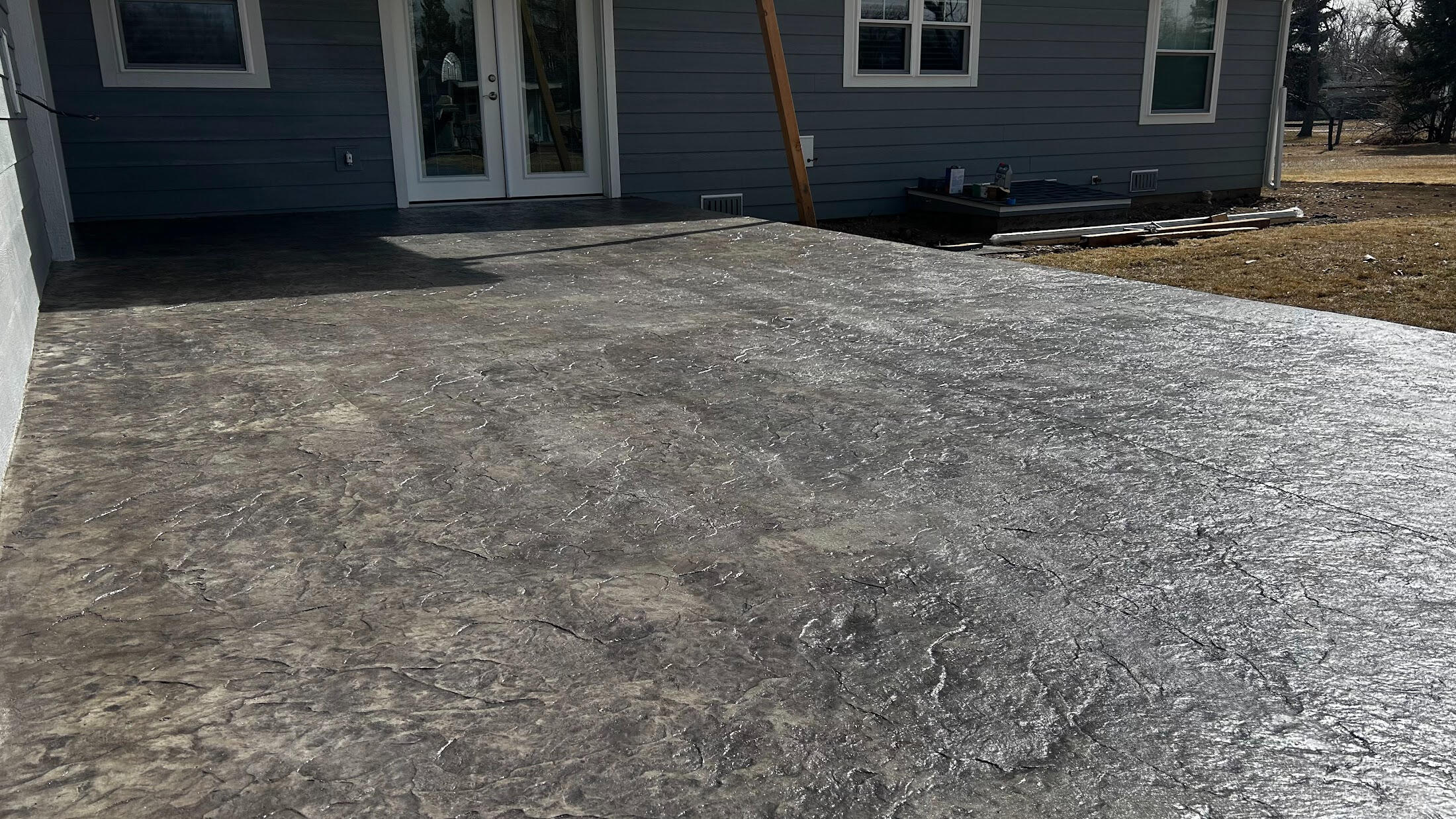 Stamped concrete backyard patio in Fort Collins, CO with a gray textured finish, ideal for low-maintenance outdoor space.