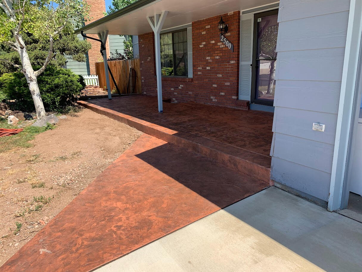 Stamped concrete front porch in Fort Collins, CO with a rich reddish-brown finish and textured pattern, designed for durability