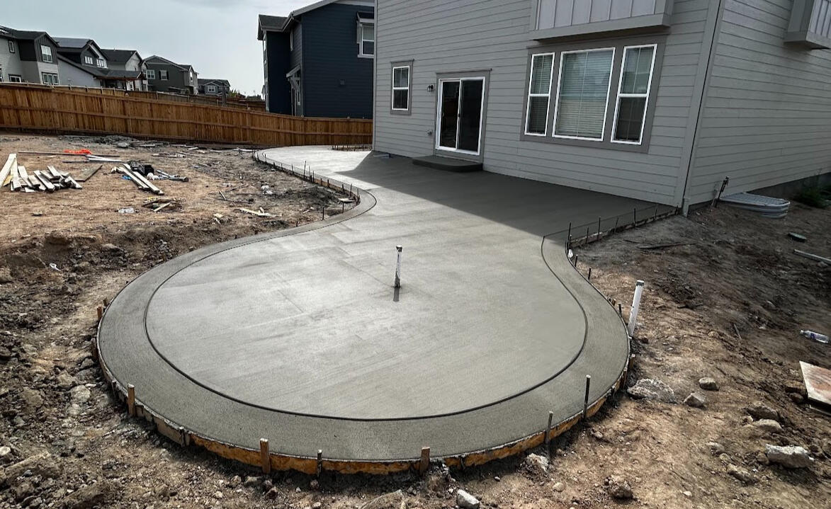Curved concrete backyard patio in Timnath, Colorado with a smooth broom finish, designed for outdoor living and entertainment