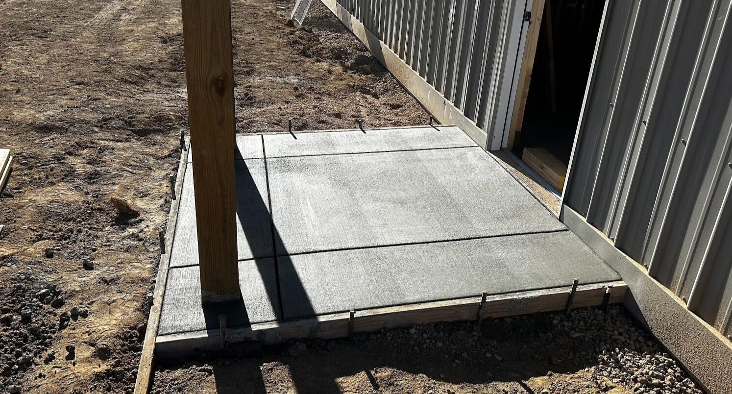 New concrete entry pad with broom finish installed outside metal building door, Northern Colorado.