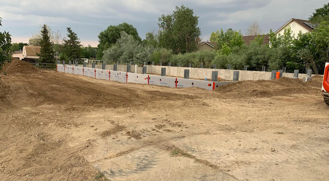 Far angle of a new residential foundation with foam insulation for a post framed building in Fort Collins, CO.