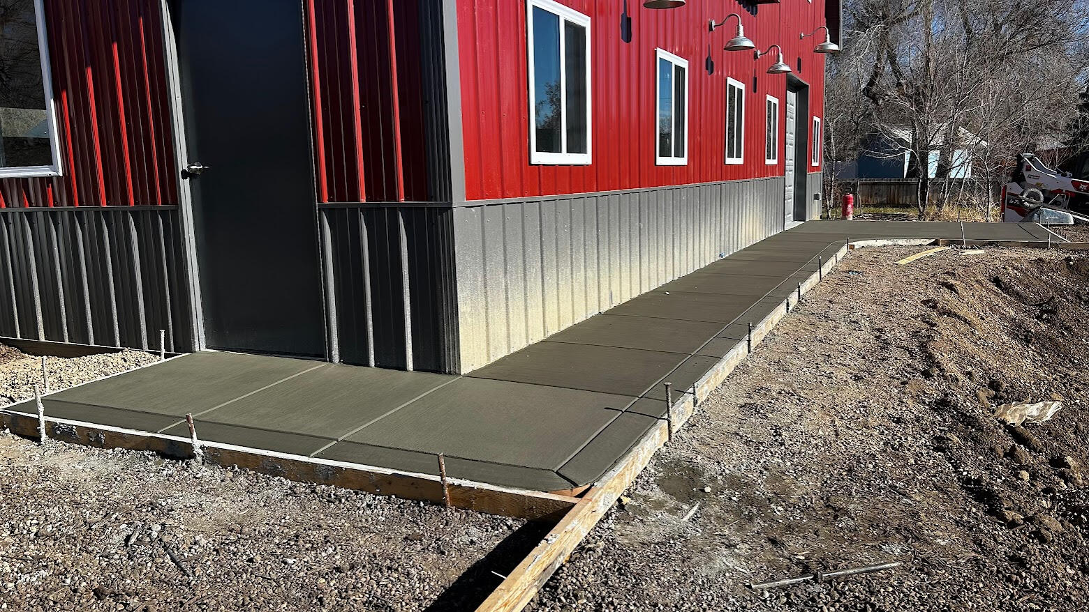 New concrete sidewalk along a red barndominium in Berthoud, Colorado.