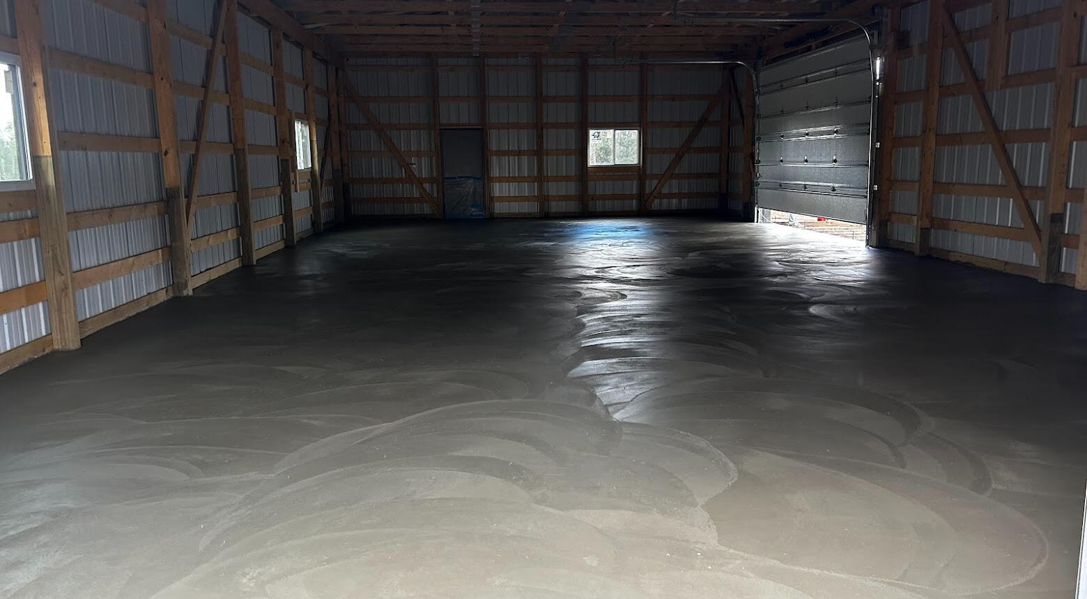 Slick troweled concrete floor inside a post framed barn building.