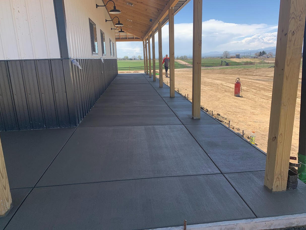 Freshly poured concrete walkway under covered porch along side a Barn style building in Fort Collins, CO.