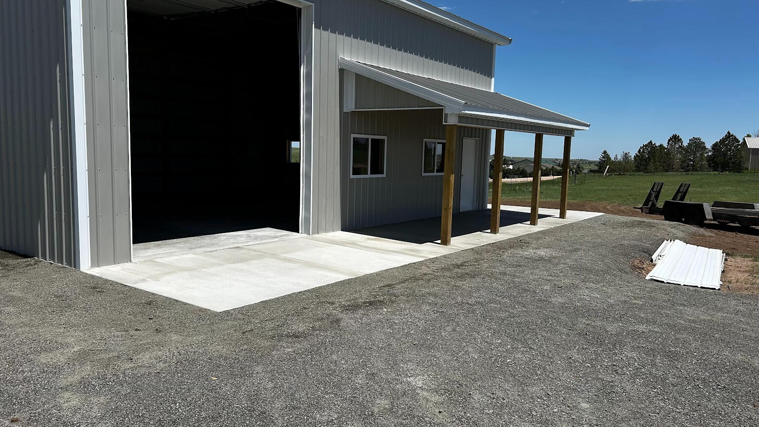 Concrete apron and covered porch slab in front of large metal shop building, in Cheyenne, Wyoming