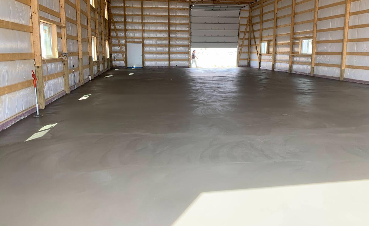 Freshly finished concrete floor inside large post frame building shop with slick trowel finish in Berthoud, Colorado