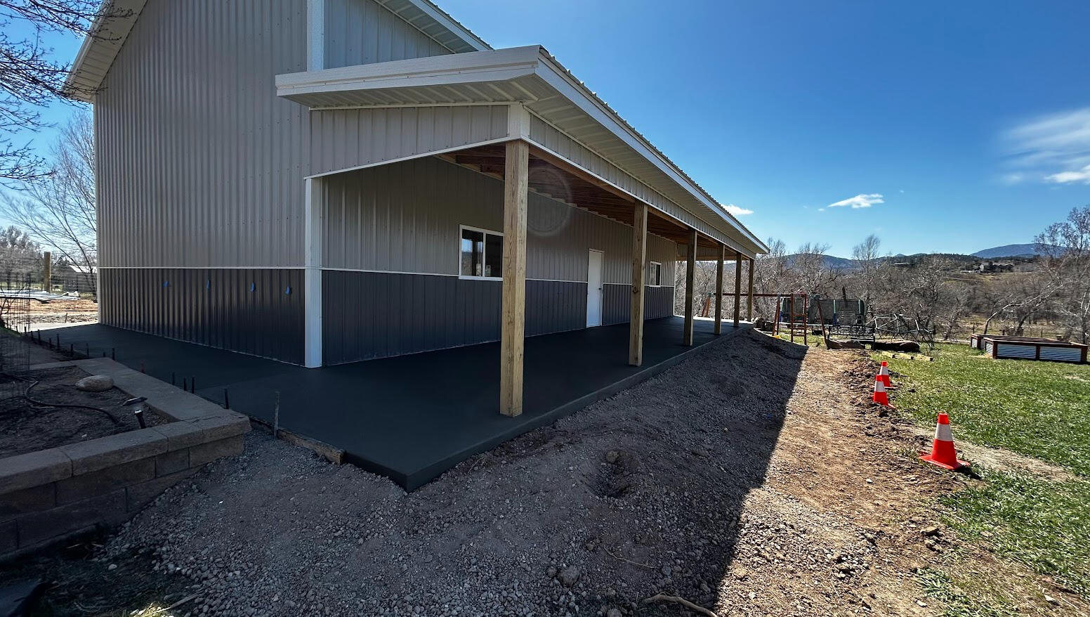 New concrete wraparound porch slab with broom finish along metal barndominium building in Loveland, CO