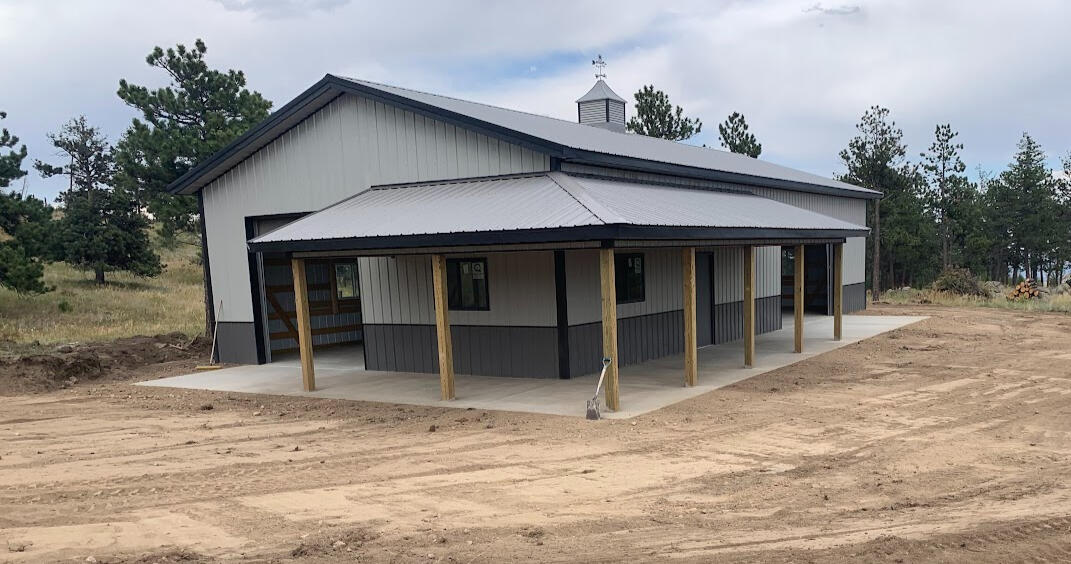 Completed concrete porch and slab surrounding metal shop building, wide rural lot with finished exterior flatwork in Bellvue, CO