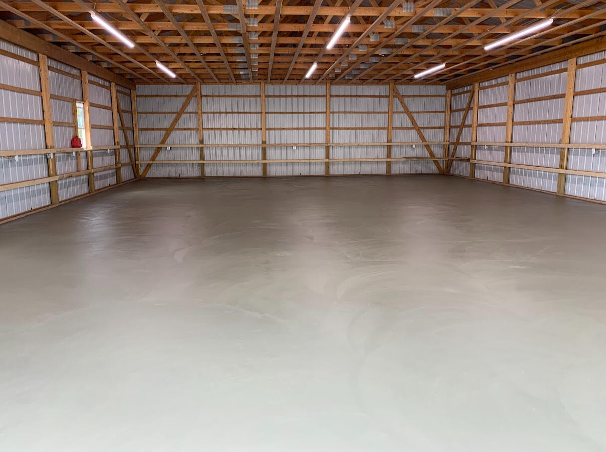 Freshly finished concrete floor inside large wood-frame shop, smooth trowel finish with open layout in Windsor, CO.
