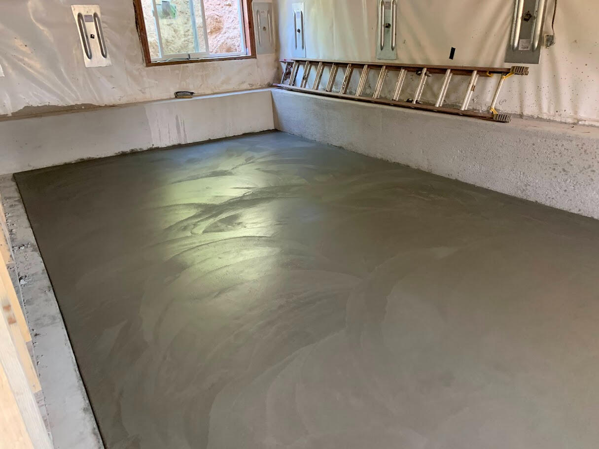 Newly poured and finished concrete floor in small basement utility room in Loveland, Colorado.